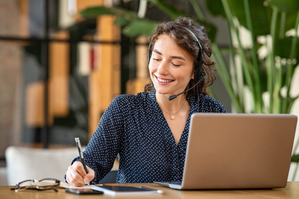 Une conseillère avec un casque téléphonique, souriante, prenant des notes