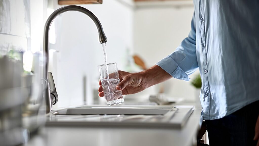 Un verre d'eau rempli au robinet de la cuisine