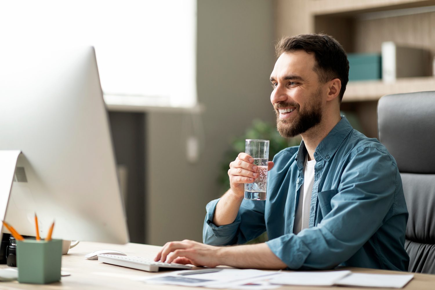 Un professionnel buvant un verre d'eau à son bureau