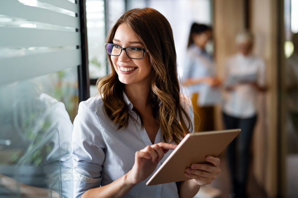 Une professionnelle souriante consultant une tablette au bureau
